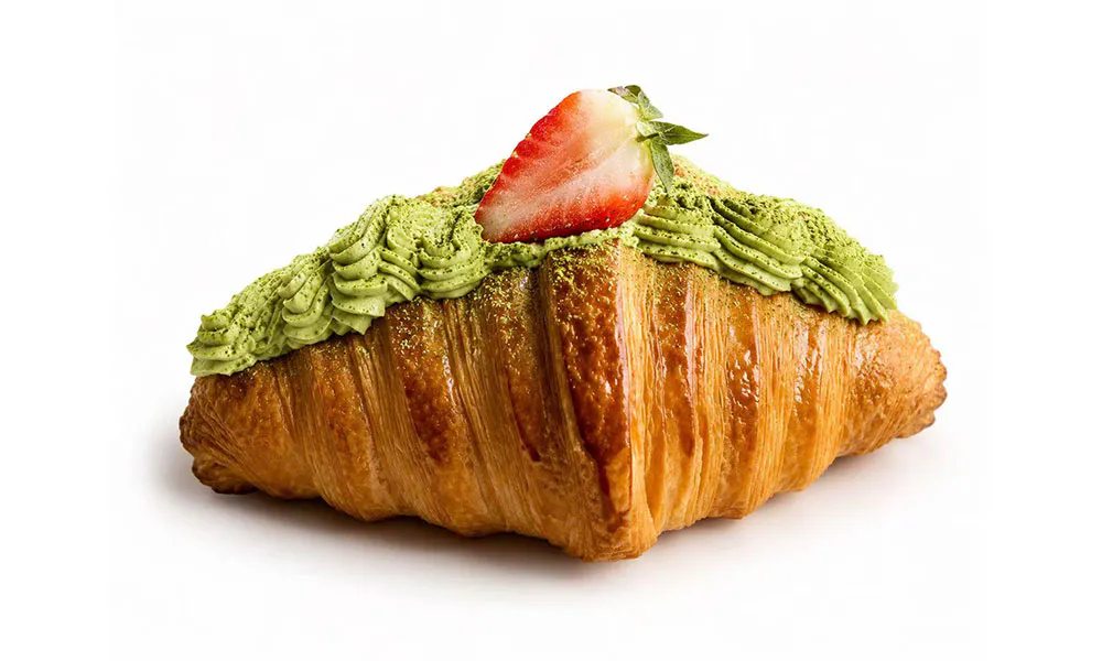 Buttery croissant topped with piped matcha cream, matcha powder and a fresh strawberry slice at Sweet Cottage Cafe, a Dessert shop in Lexington