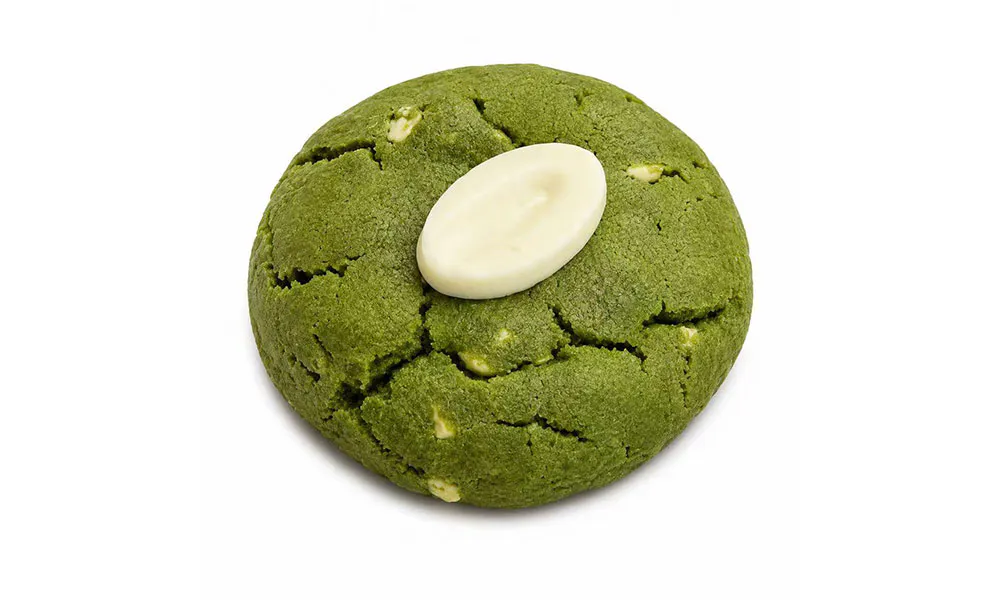 Cracked matcha green cookie with single oval white chocolate piece centered on top at Sweet Cottage Cafe, a Dessert shop in Lexington