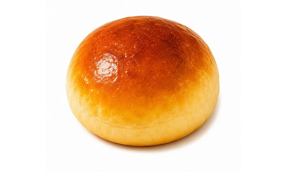Round soft golden baked milk bun with smooth gradient glazed crust against white backdrop at Sweet Cottage Cafe, a Dessert shop in Lexington