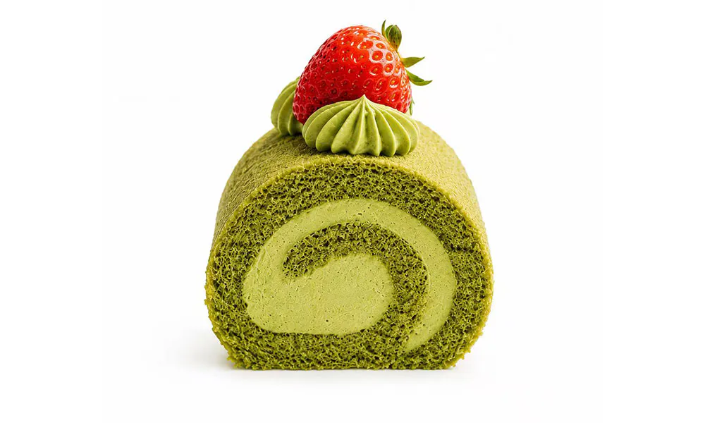 Matcha swiss roll cake with green sponge, matcha cream filling, whipped cream and whole strawberry garnish at Sweet Cottage Cafe, a Dessert shop in Lexington